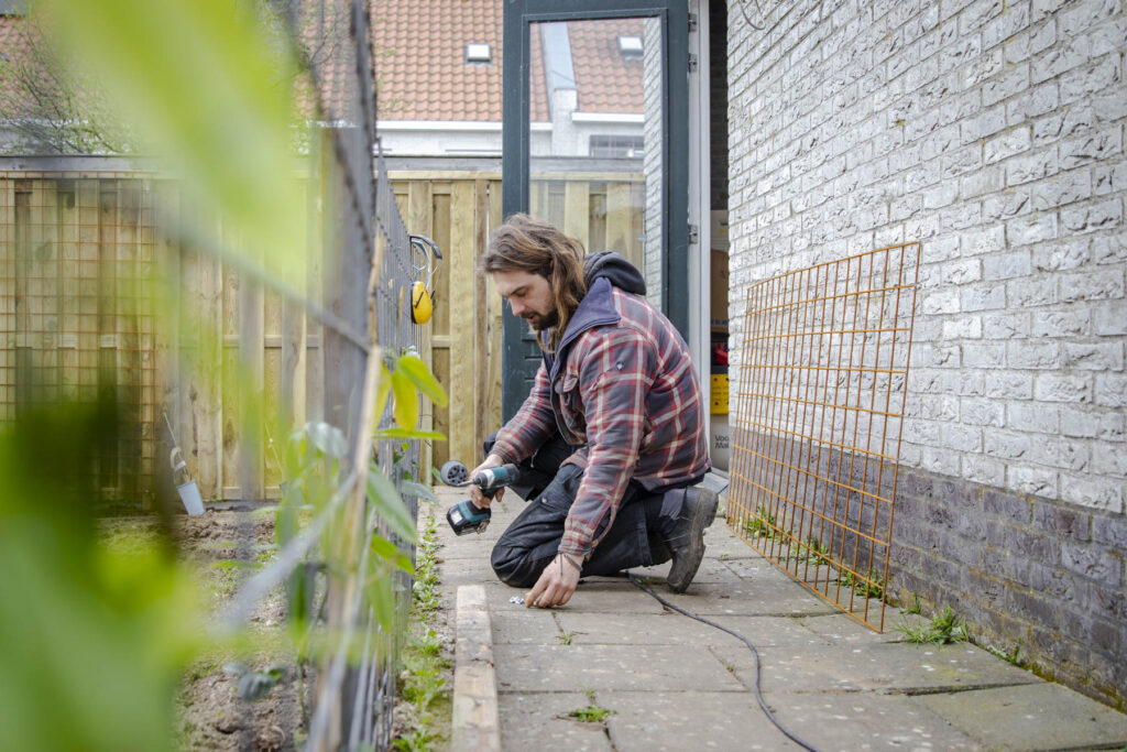 Foto van tuinaanleg in borne. Beplanting, schutting en moestuin.